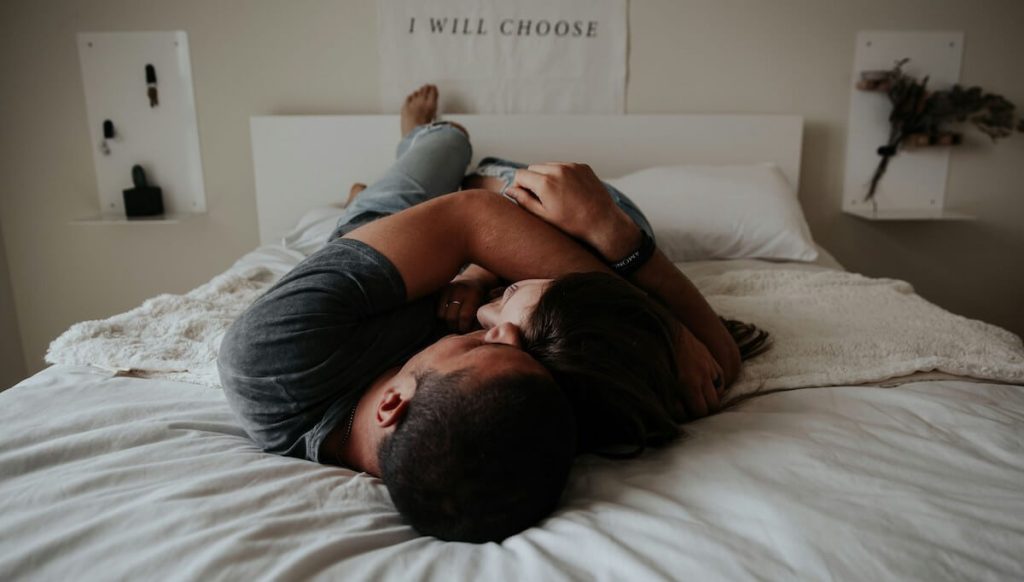 man and woman hugging on bed