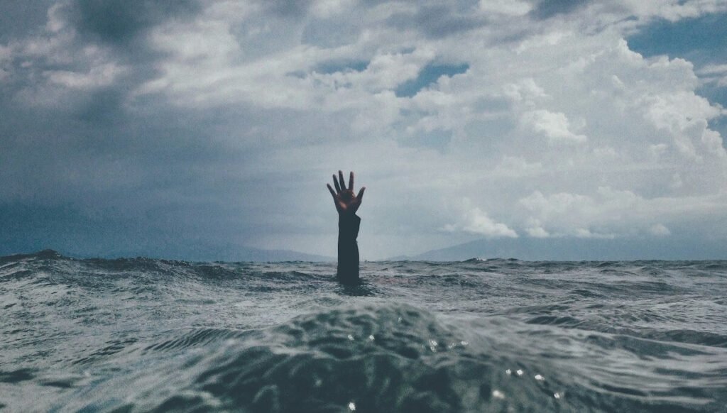 drowning person reaches hand out of ocean